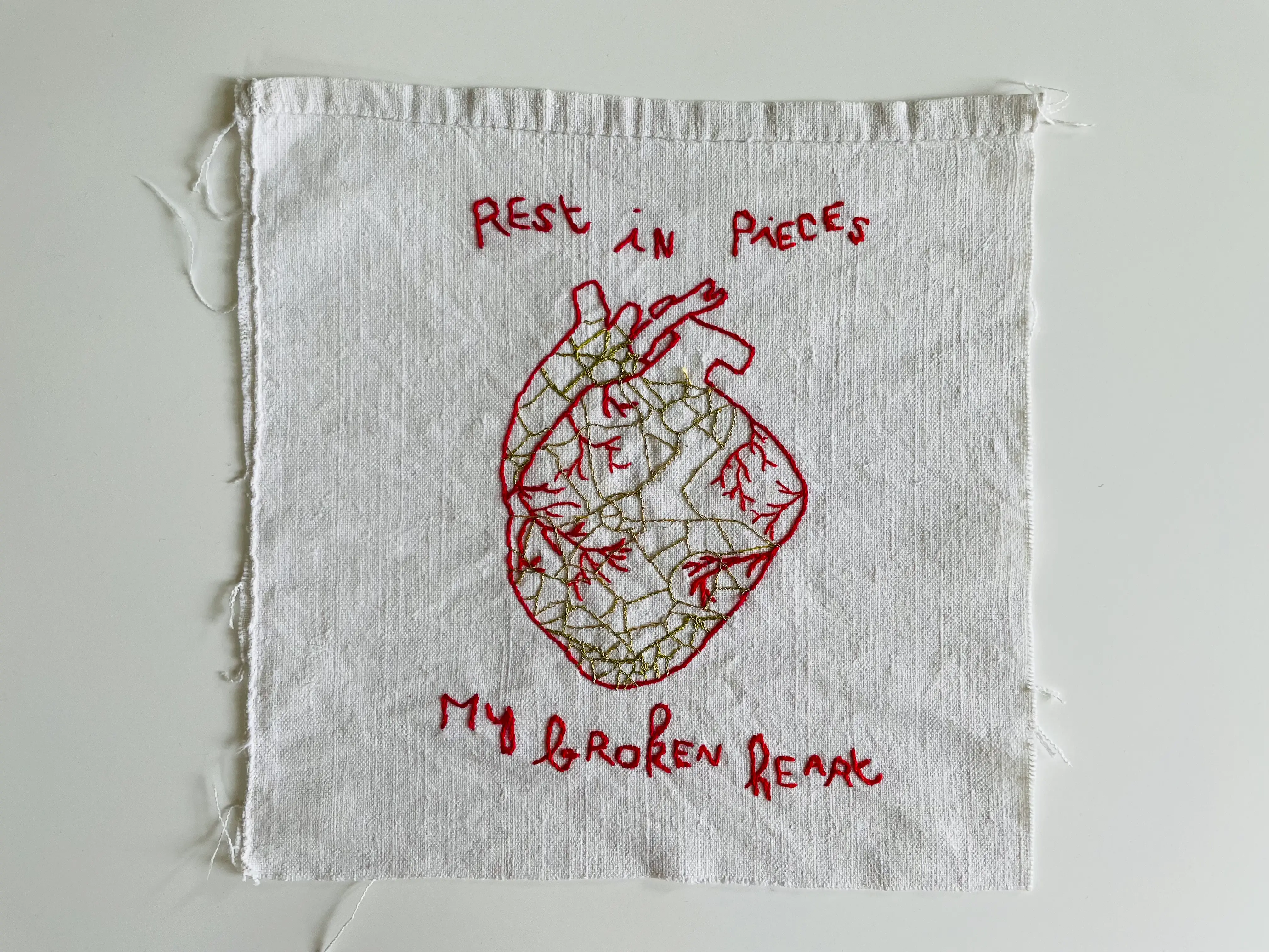 Coeur brodé à la main au fil rouge entier mais en mille morceaux cousus entre-eux par du fil d'or. Inscription brodée au fil rouge : Rest in pieces my broken heart. Oeuvre d'art textile contemporain de l'artiste Mai Khanh Pham To