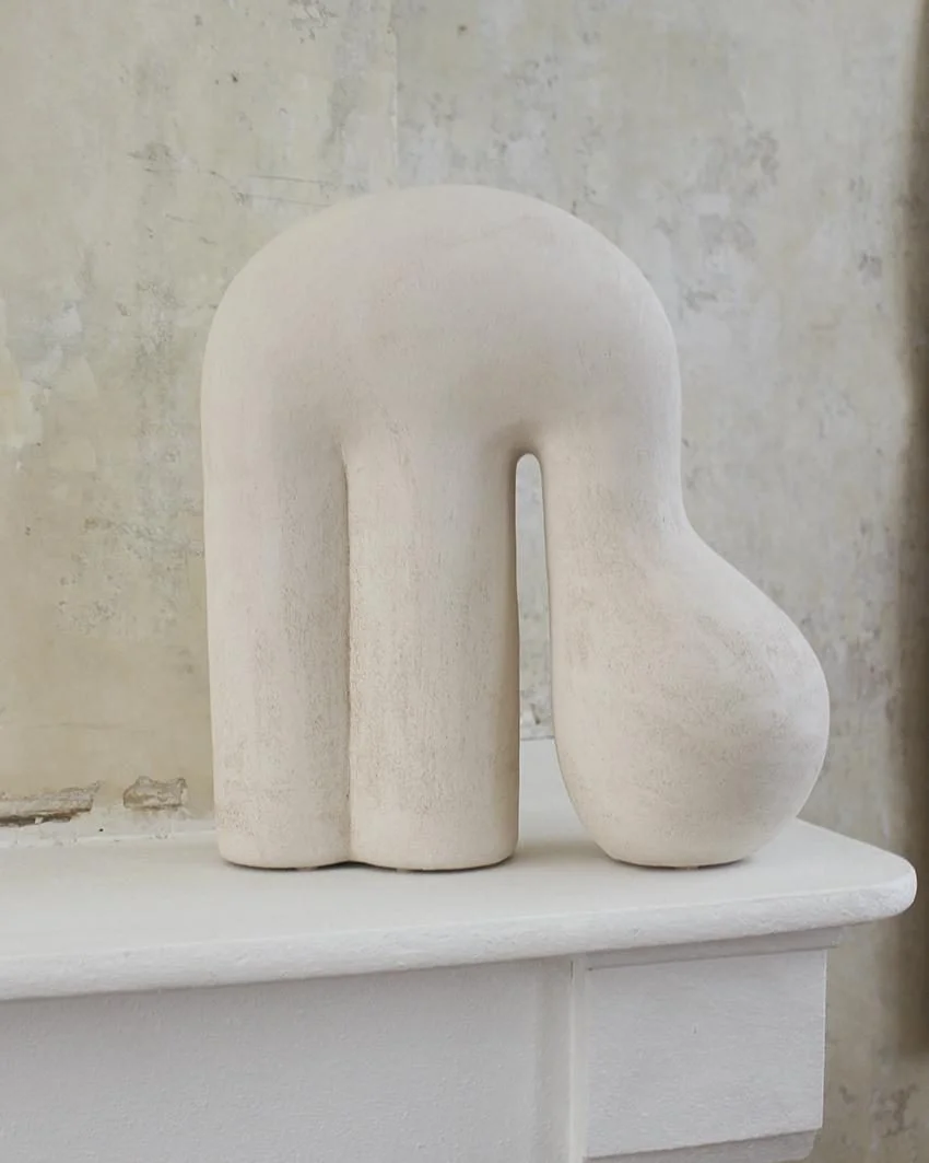 Sculpture Nuit blanche #27 d'Elisa Uberti en grès blanc, petite forme à deux jambes arquées surmontées d'une masse arrondie, posée sur une cheminée