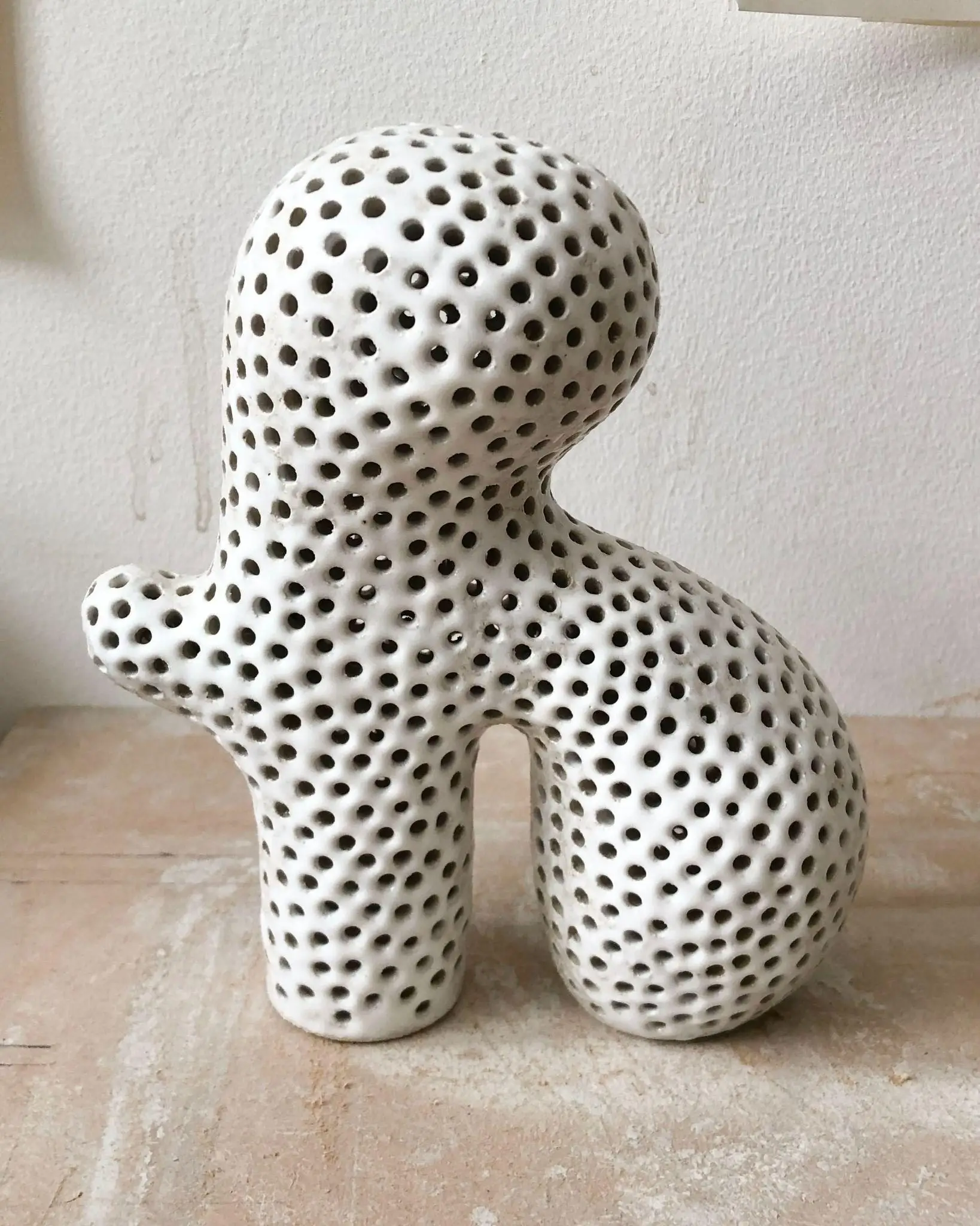 Petite sculpture Tiny #17 d'Elisa Uberti en grès émaillé blanc perforé de multiples trous, silhouette anthropomorphe aux jambes arquées