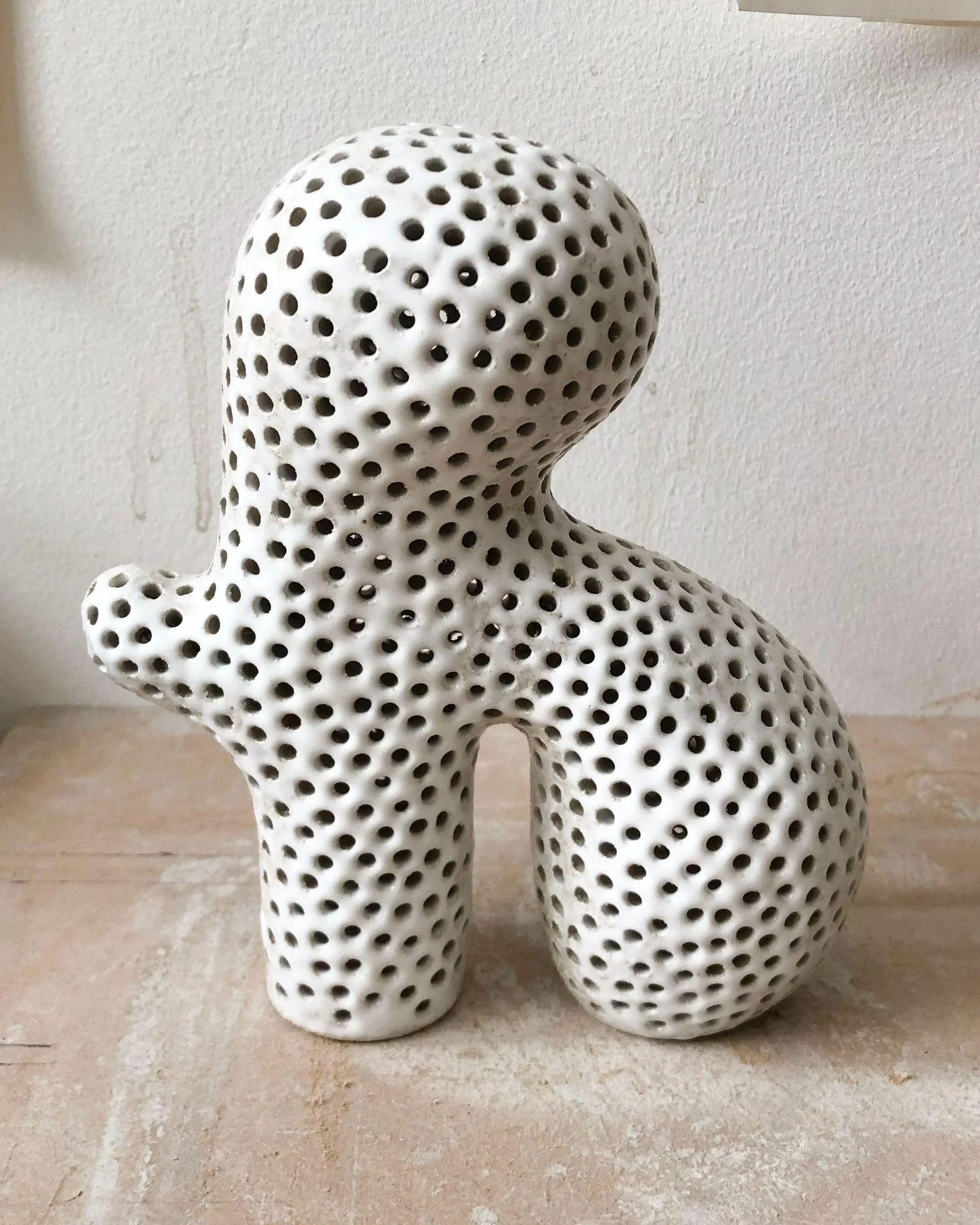 Petite sculpture Tiny #17 d'Elisa Uberti en grès émaillé blanc perforé de multiples trous, silhouette anthropomorphe aux jambes arquées