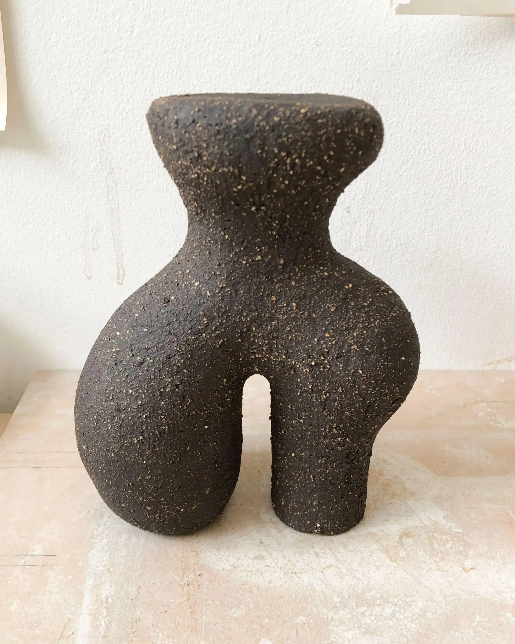 Petite sculpture Tiny #19 d'Elisa Uberti en grès noir grainé, silhouette anthropomorphe aux jambes arquées et à la texture granuleuse